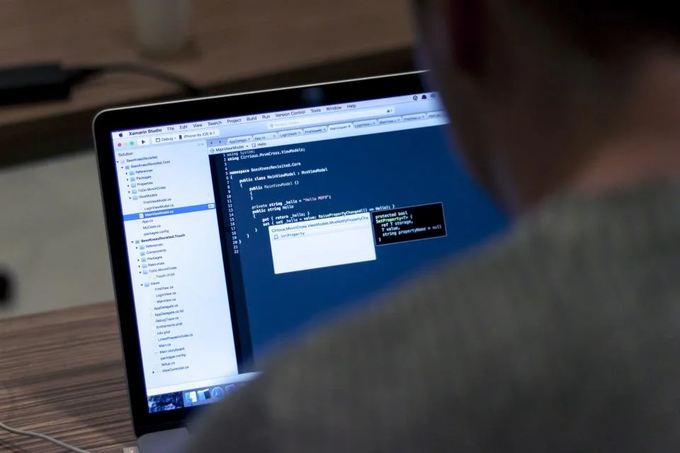 Mesa de programador com notebook exibindo código durante sessão de trabalho